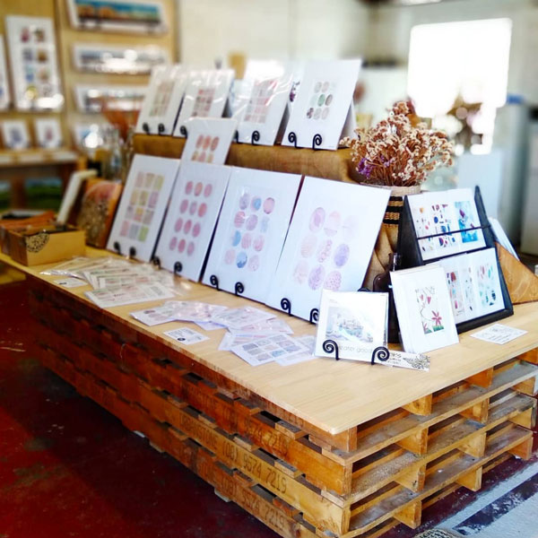 The wooden display table covered in art prints by Mandy 
