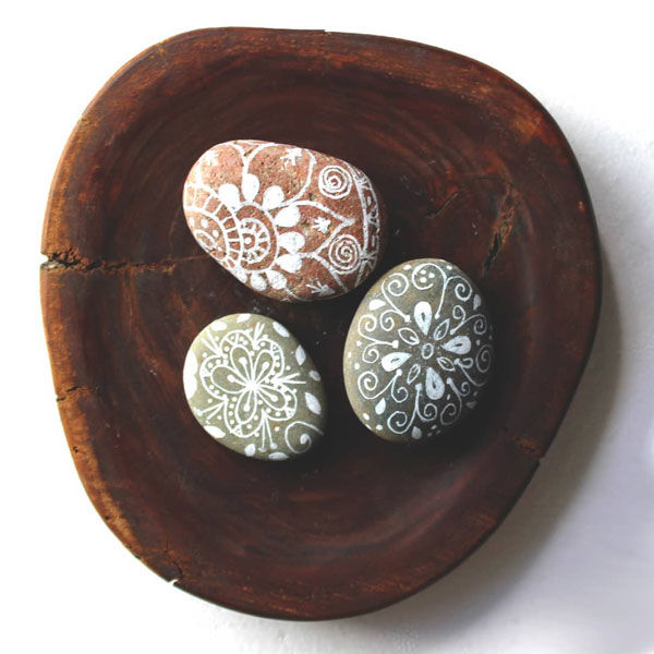 3 small painted rocks displayed on a wooden platter